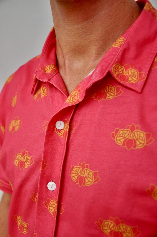 Een persoon draagt een custom roze overhemd met gele rozenprint.