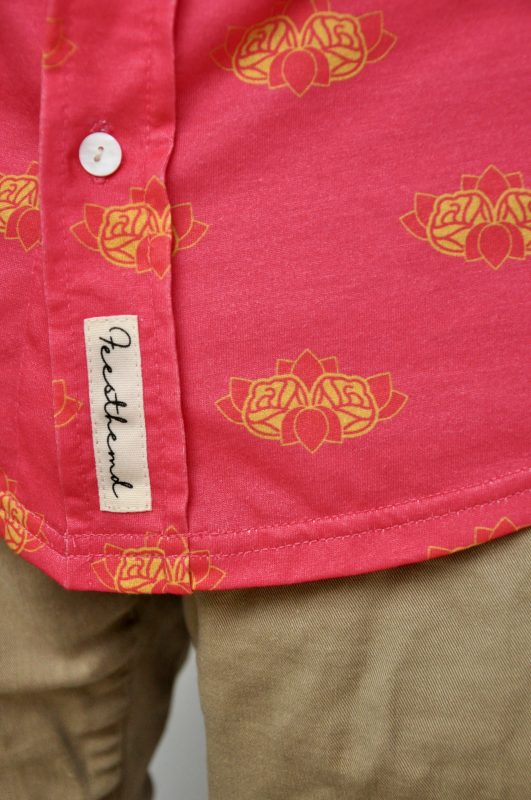 Een custom roze overhemd met gouden rozenprint en een Feesthemd merklabel op de zoom.