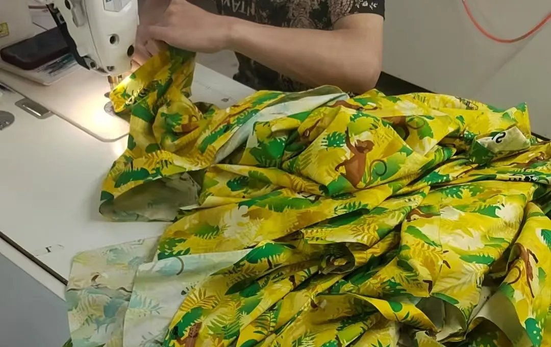 De geprinte stof van het Apenshot-hemd wordt met de hand genaaid